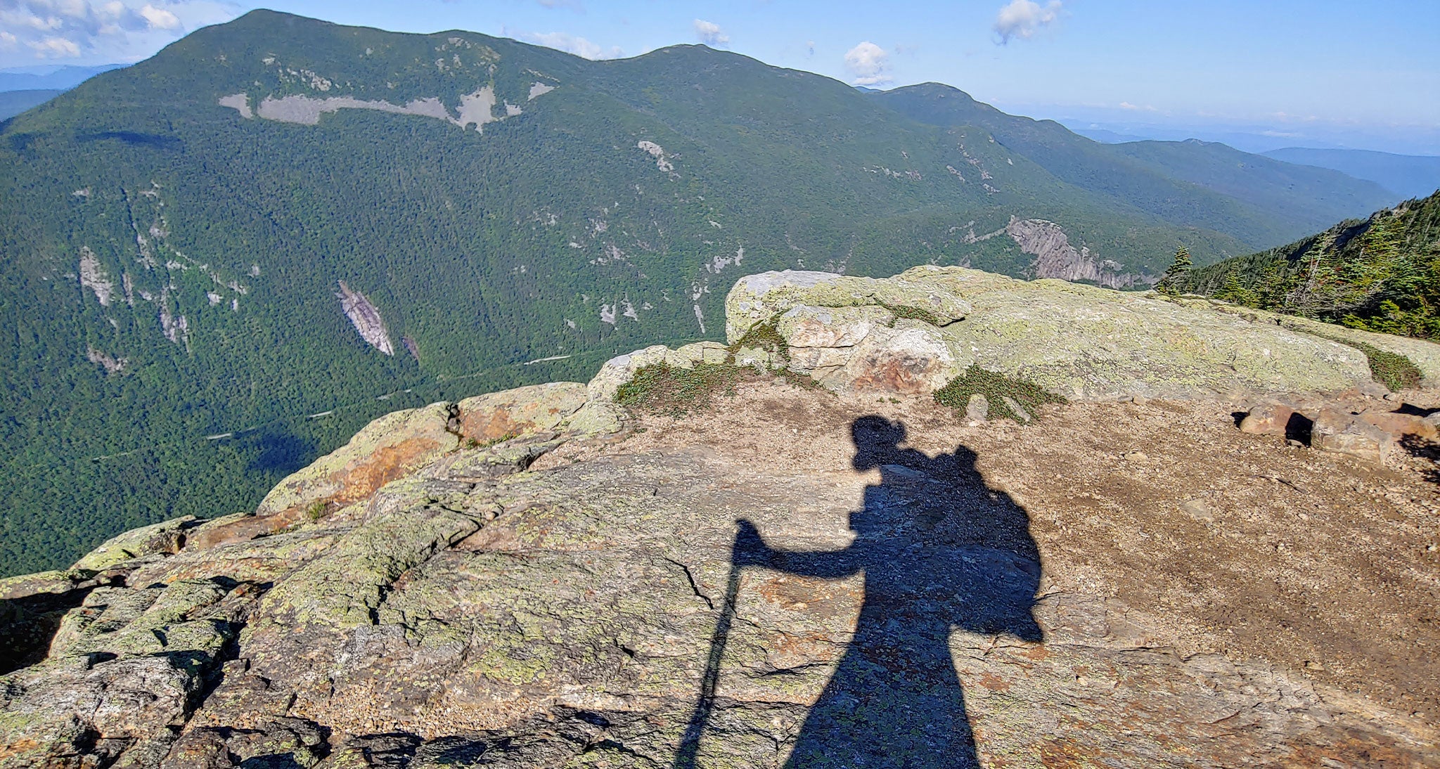 The shadow of a hiker on top of a mountain.