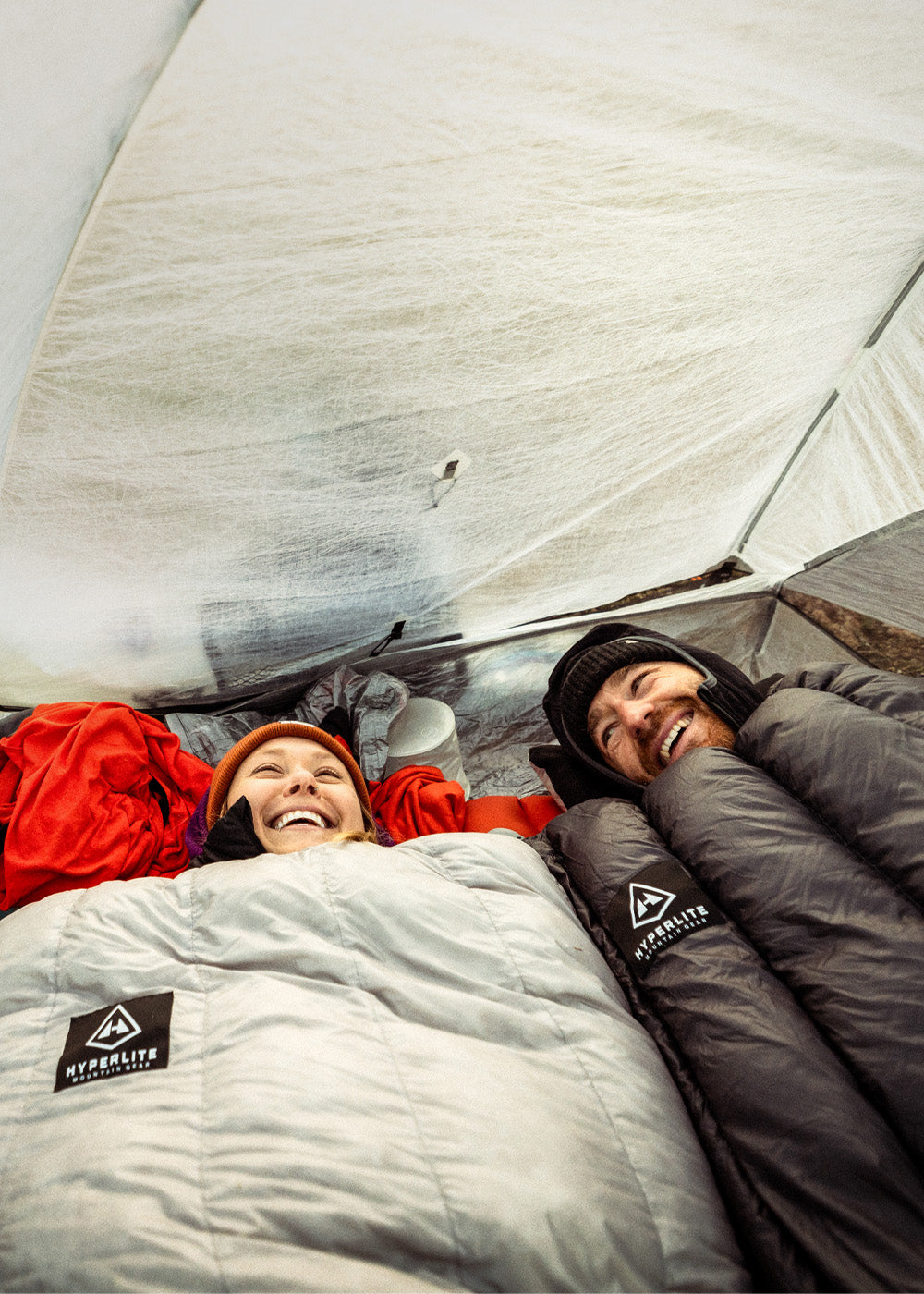 Two people lying inside a CrossPeak 2 tent with Hyperlite Mountain Gear sleeping bags.