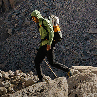 Ultralight backpacker trekking across a rocky, mountain landscape with a Hyperlite Mountain Gear pack.