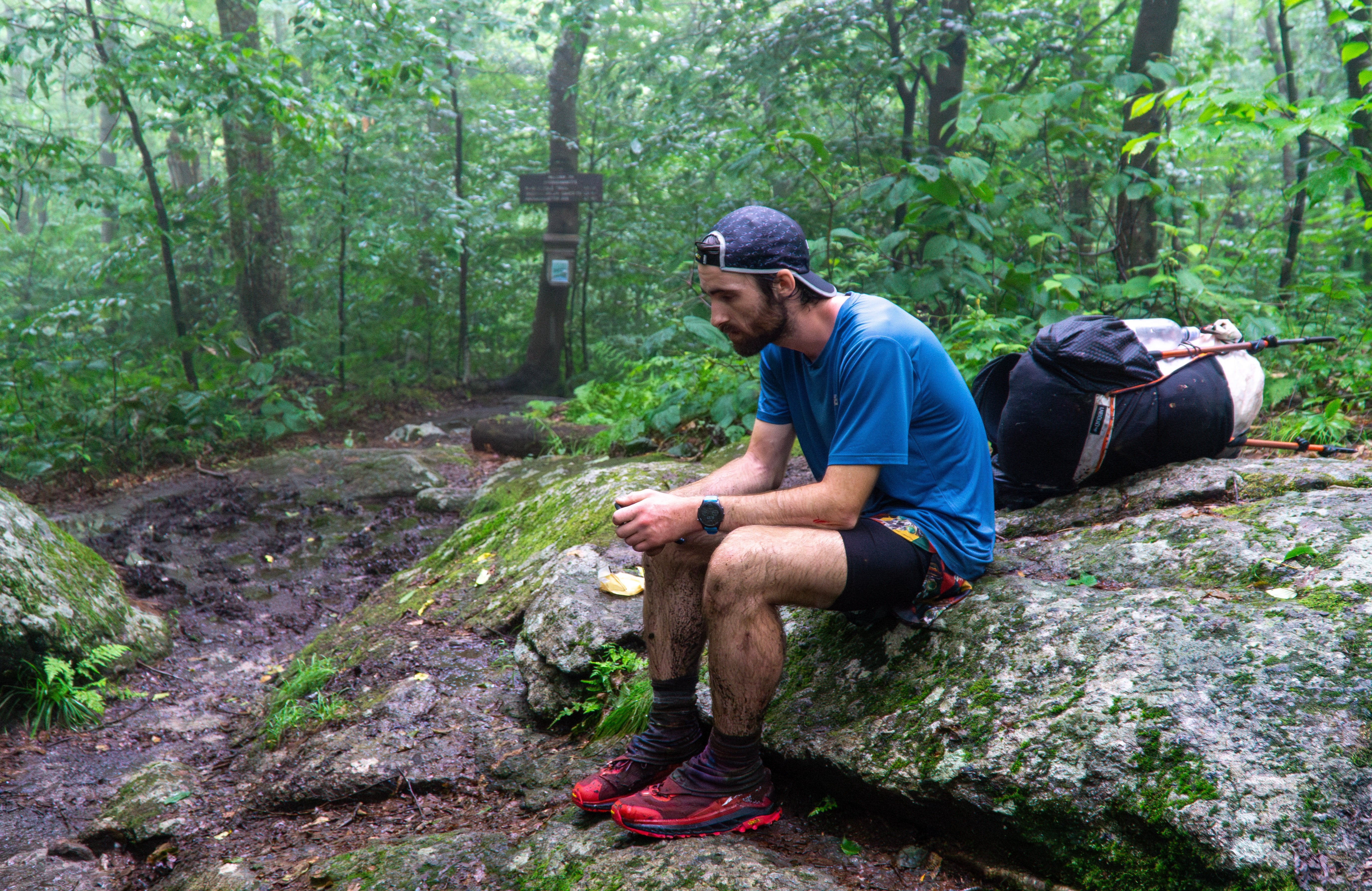 a worn hiker rests on a large rock