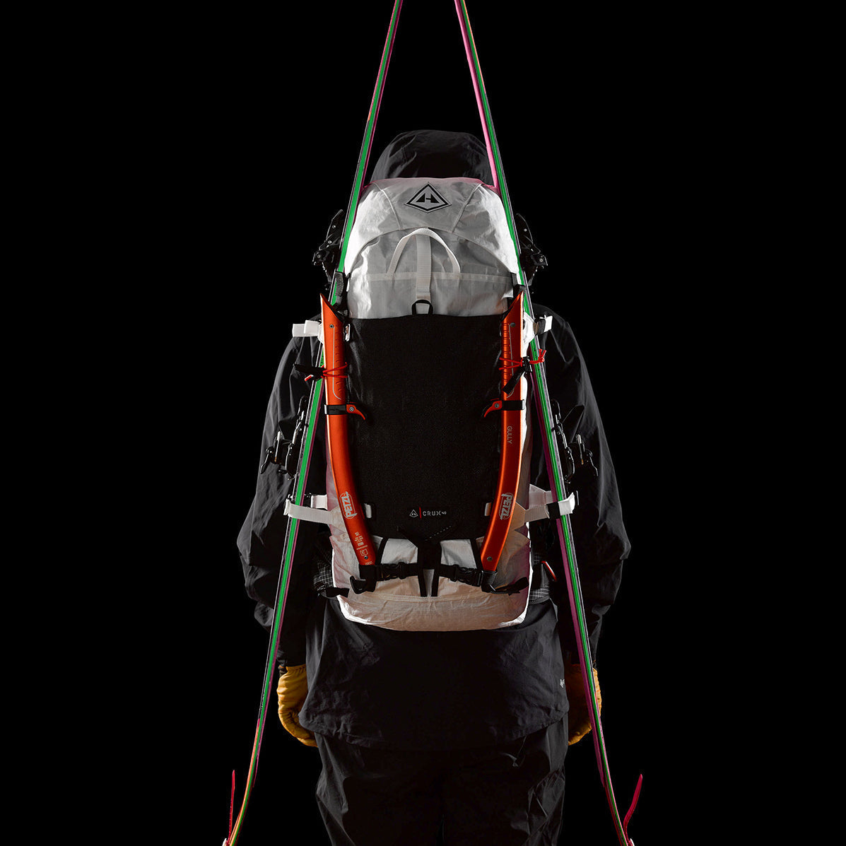 Skiier wearing the Hyperlite Mountain Gear Crux 40 with skis attached using the a-frame carry