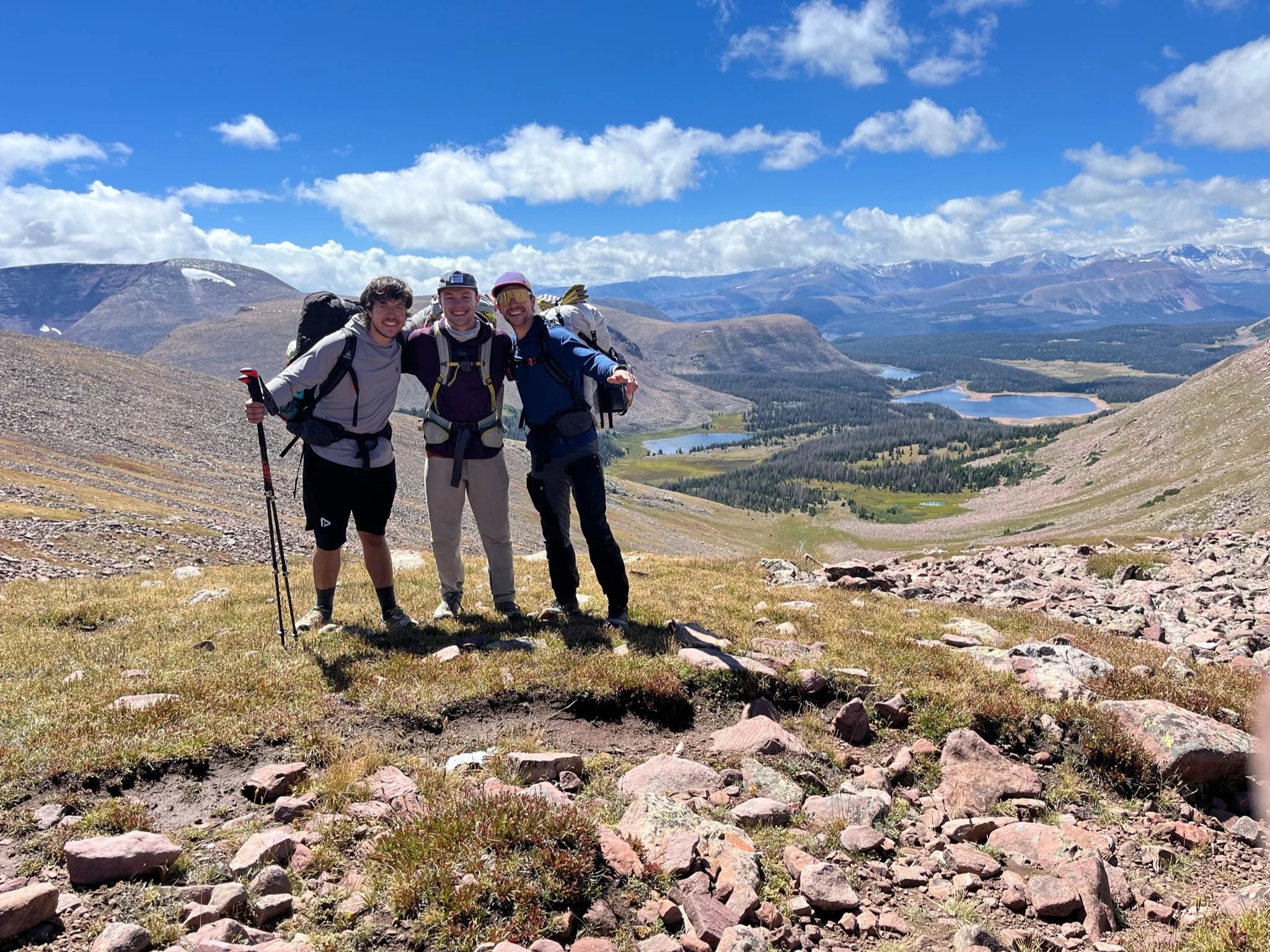 three hikers pose in front of mountain scenery
