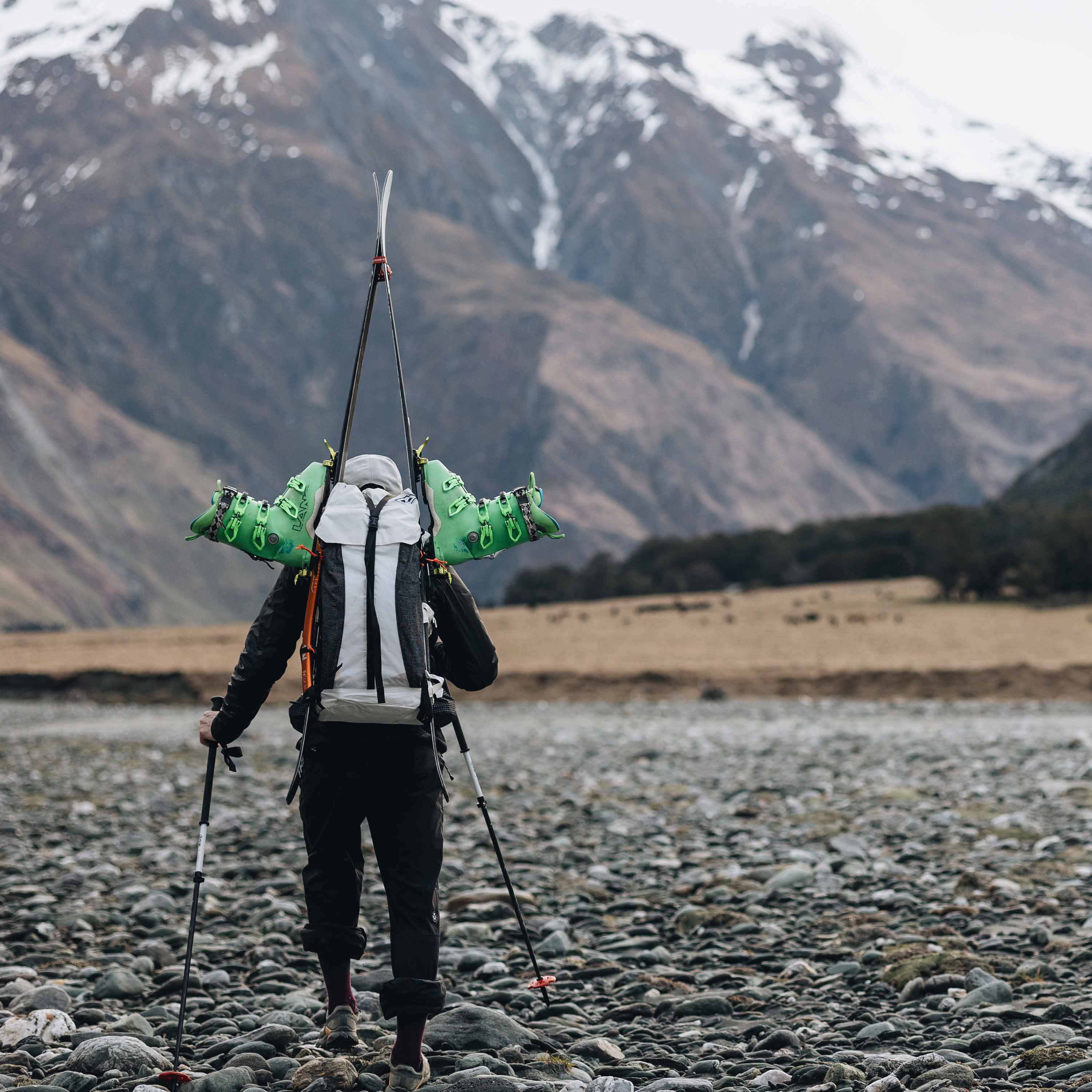 Hiker approaching a mountain with the Hyperlite Mountain Gear Headwall 55 used to carry skis using the A-frame carry method