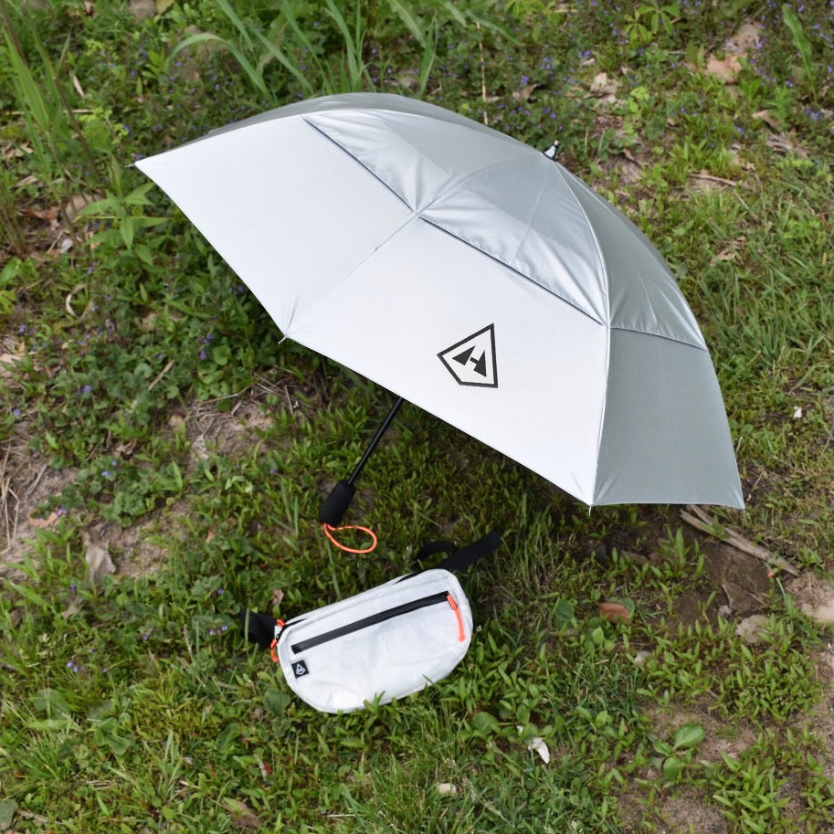 The Hyperlite Mountain Gear Versa and Essential Umbrella laying on the grass, both a part of the Runabout Bundle