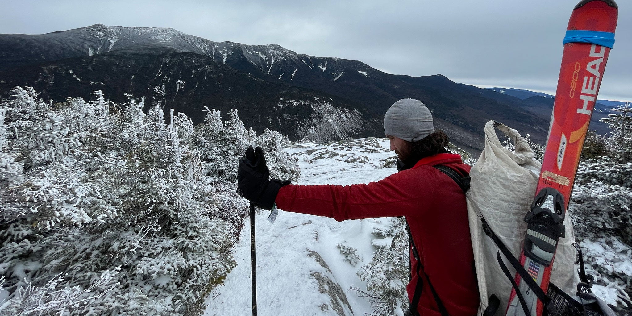 A man with skis and a backpack on a snowy trail.