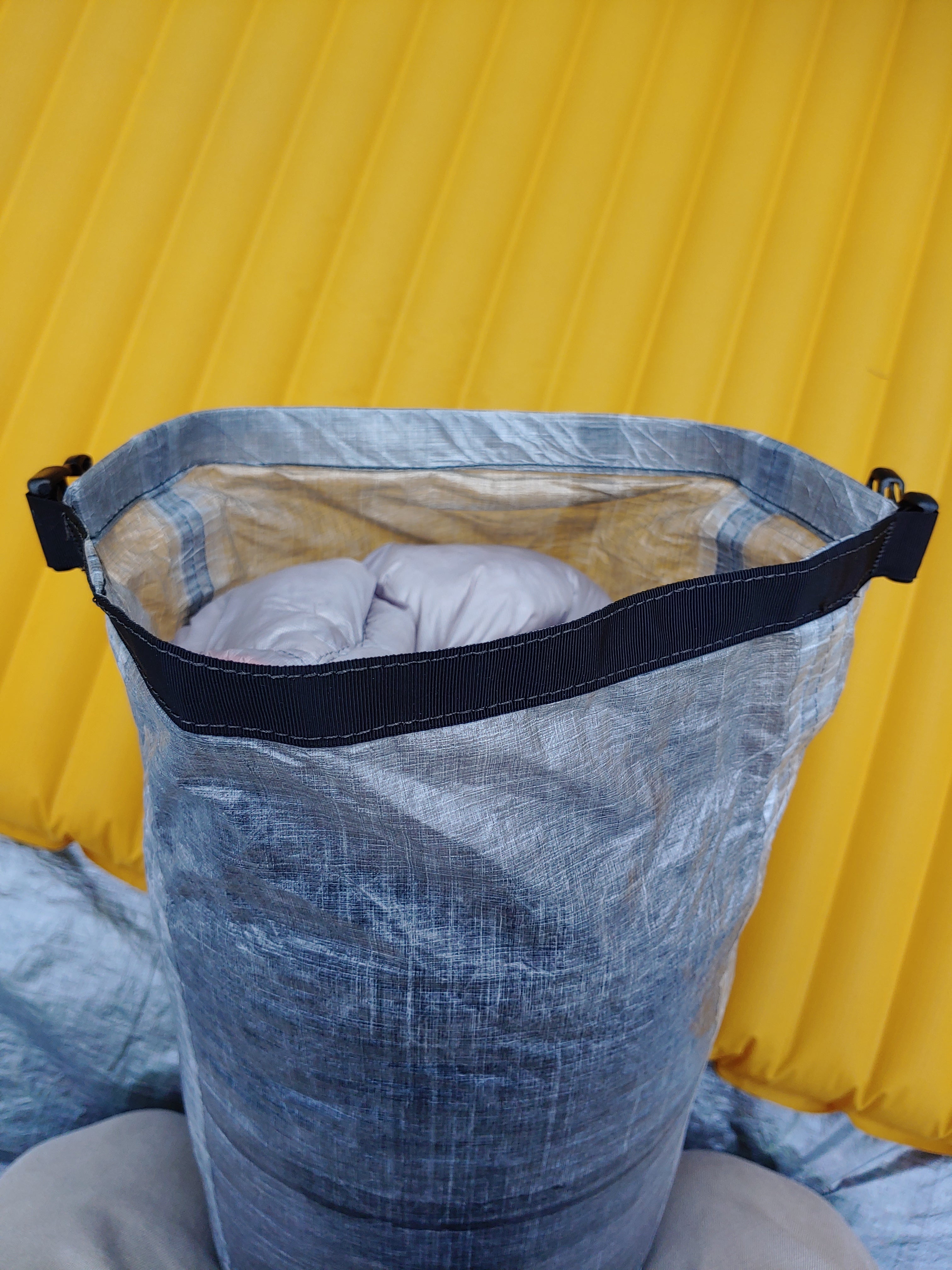 A sleeping bag sitting on top of a yellow tarp.