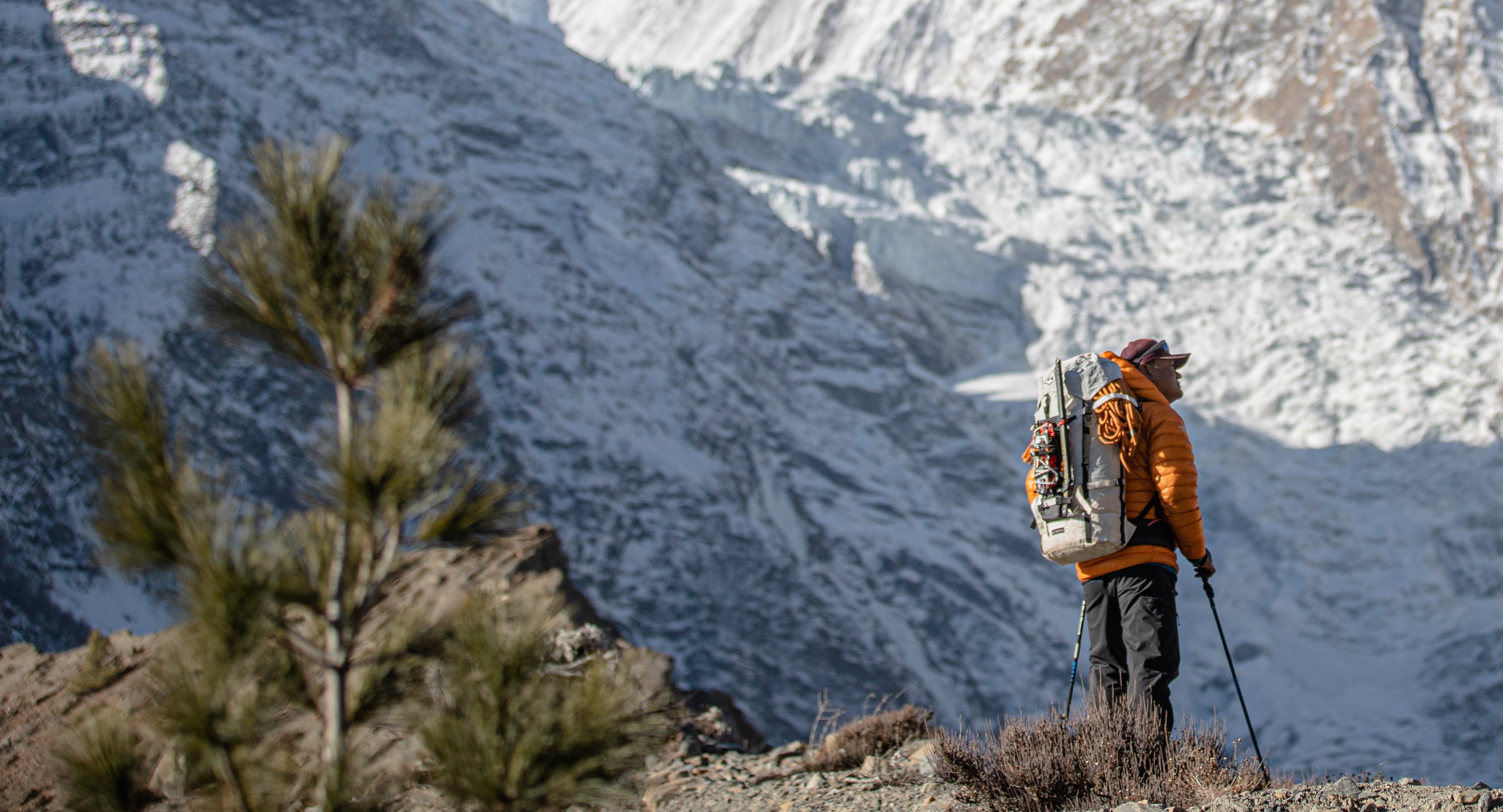 A man is standing in front of a snow covered mountain.