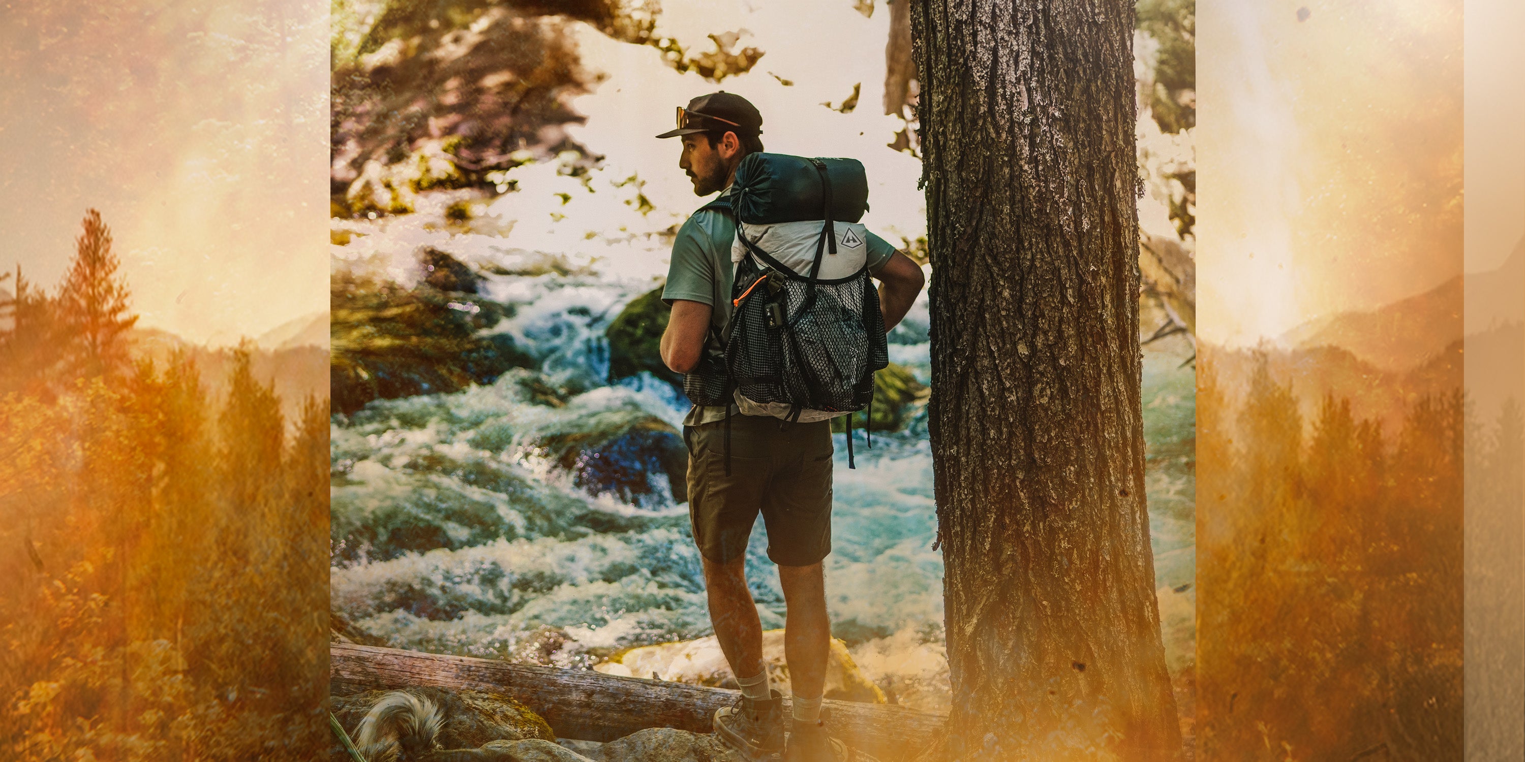 Hiker with Hyperlite Mountain Gear backpack standing by a river with a scenic background