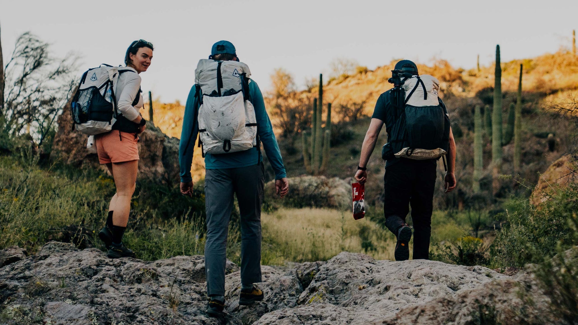 Three people hiking on a rocky trail with backpacks