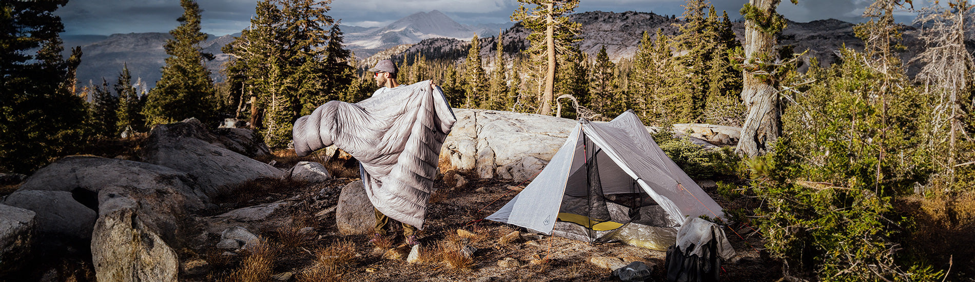 A camper sets up camp in the wilderness, enjoying the peace and quiet of nature. The mountains in the background provide a stunning backdrop for the perfect outdoor adventure.