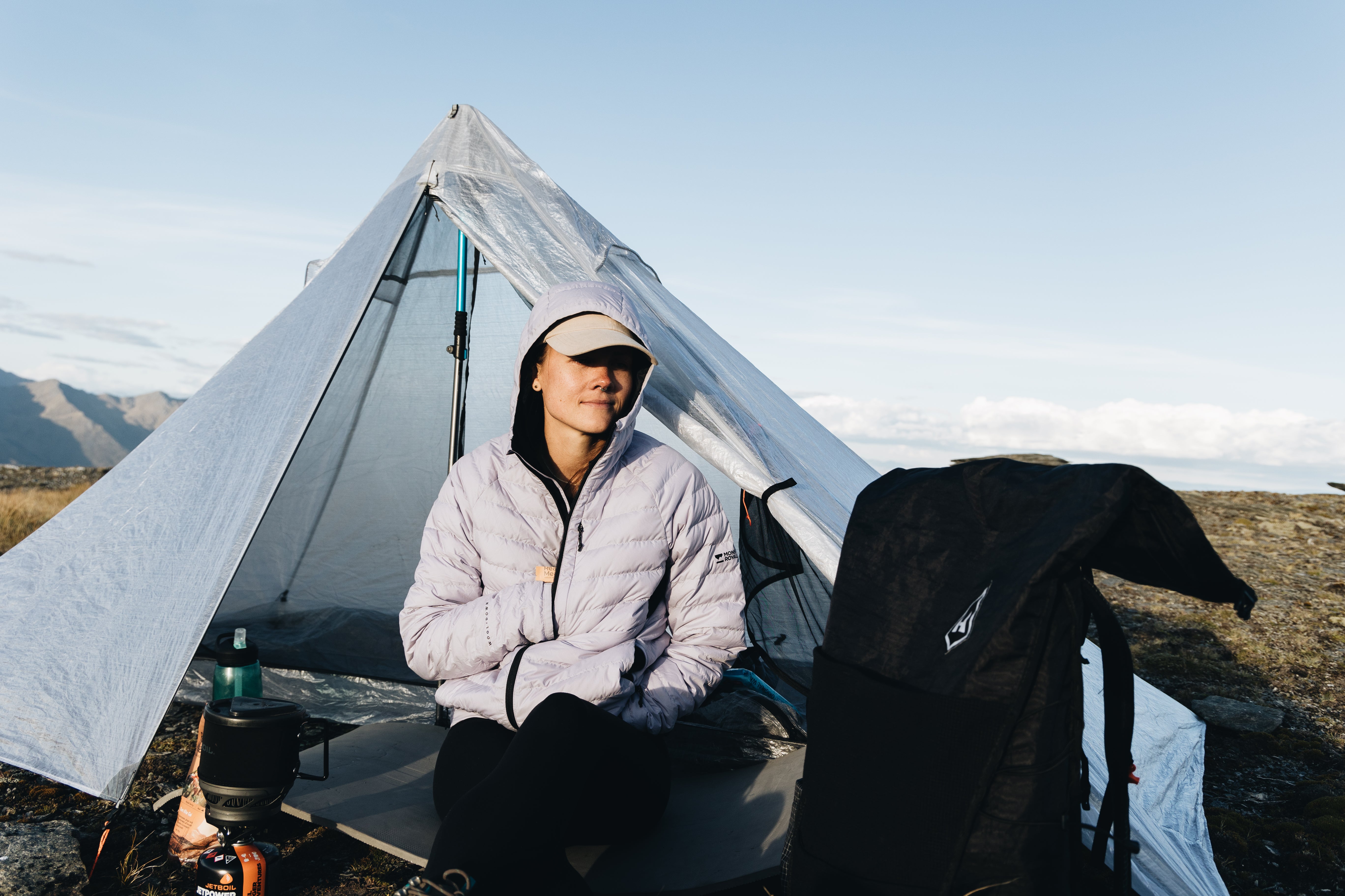 A woman sitting in front of a tent.