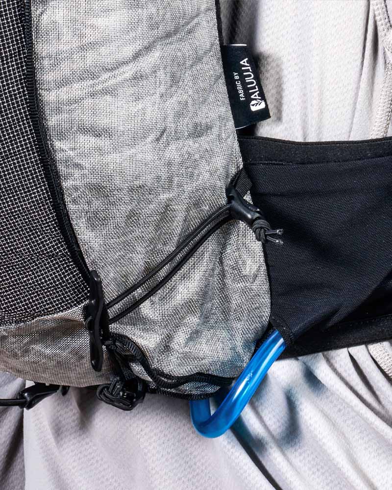 Hyperlite Mountain Gear Pemi 15 backpack with a blue carabiner attached, featuring the fabric 'ALUULA'.