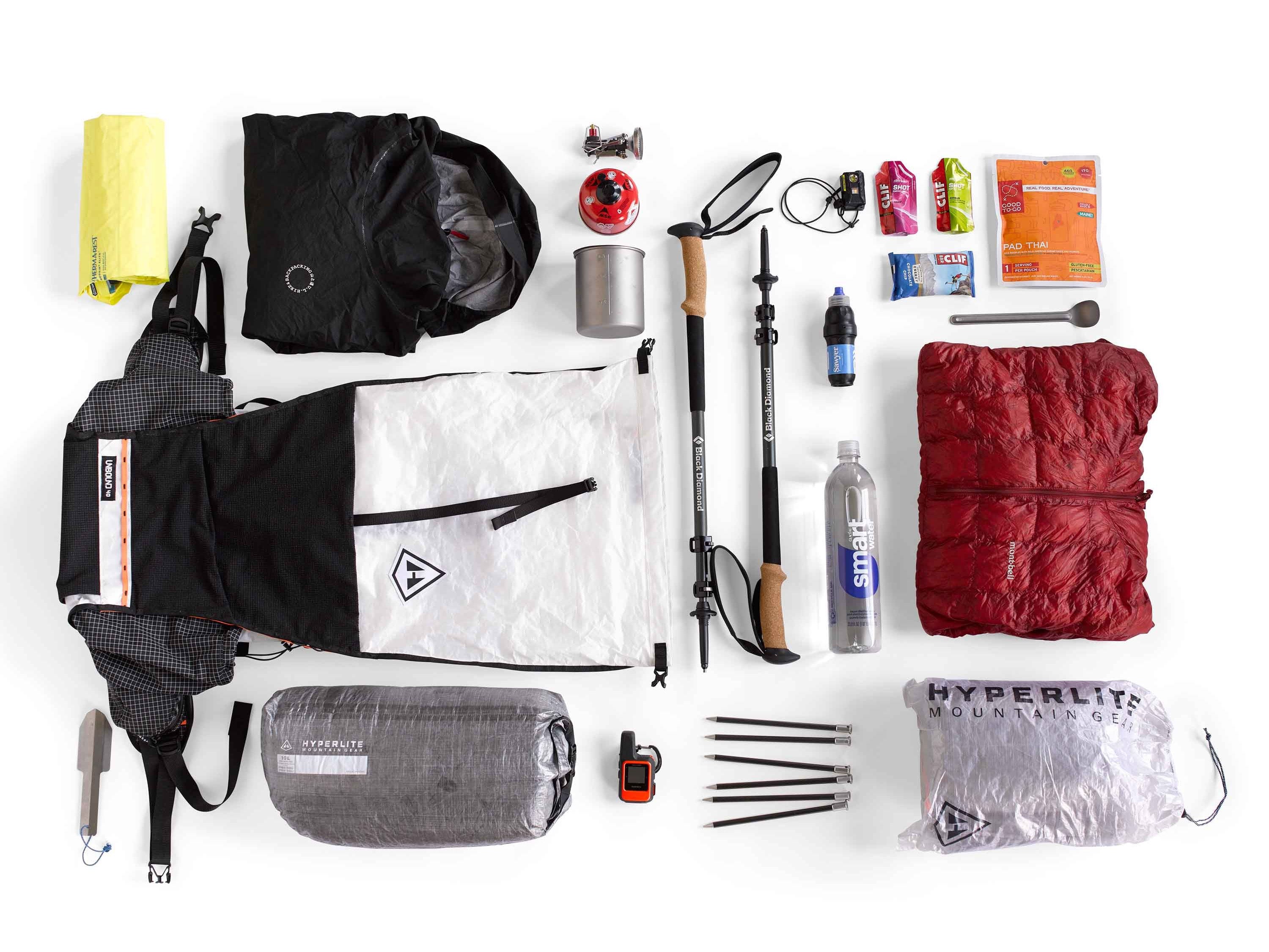 The contents of a backpack are laid out on a white surface.