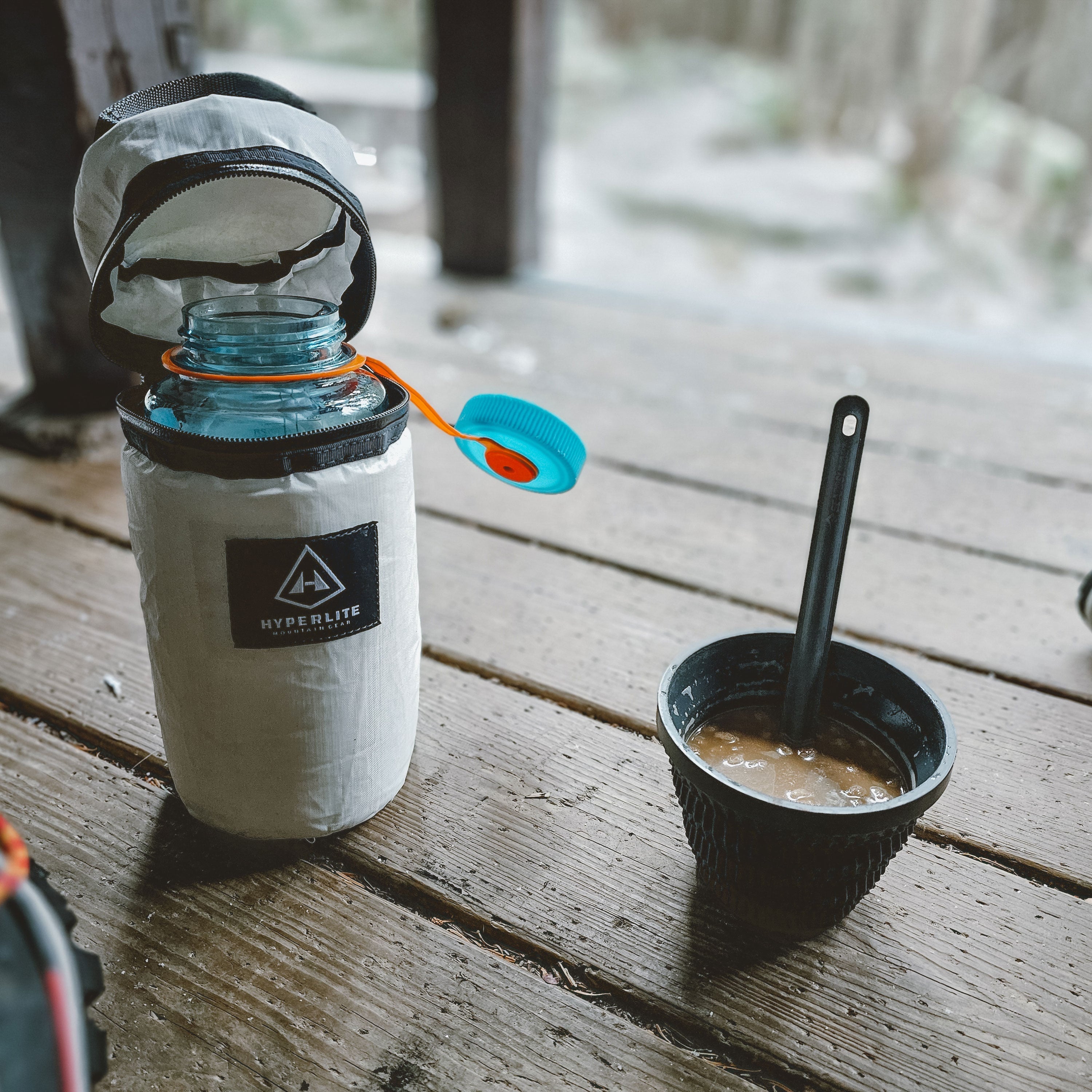 A camp meal sits beside the Hyperlite Mountain Gear Insulator in the lean to during winter time