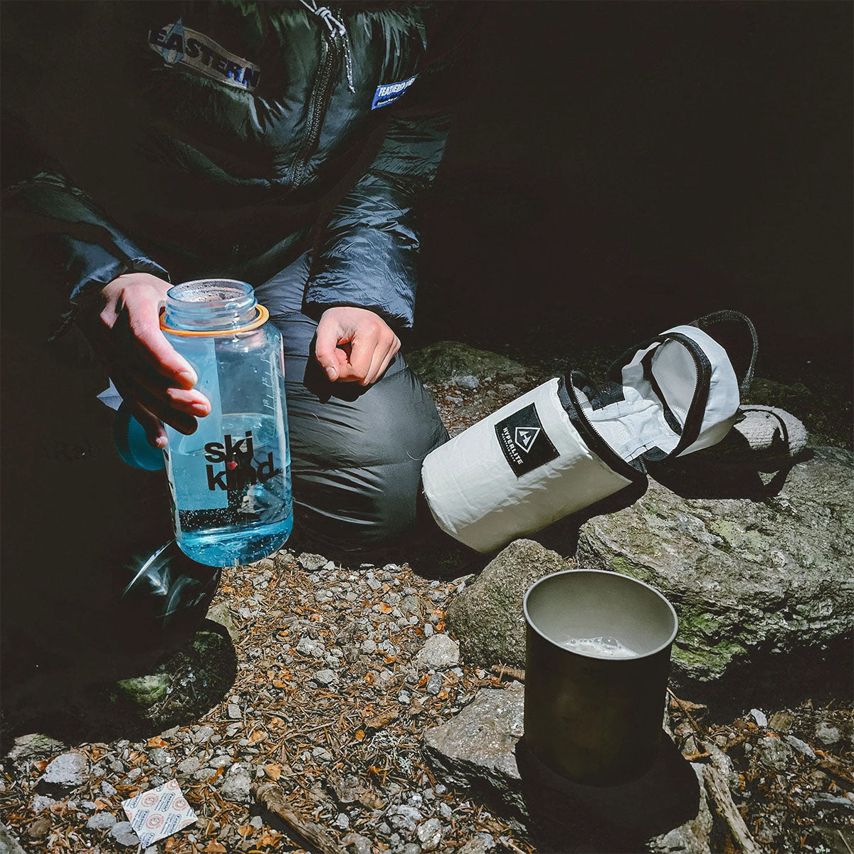At night time a hiker using the Hyperlite Mountain Gear Insulator while prepping their camp meal