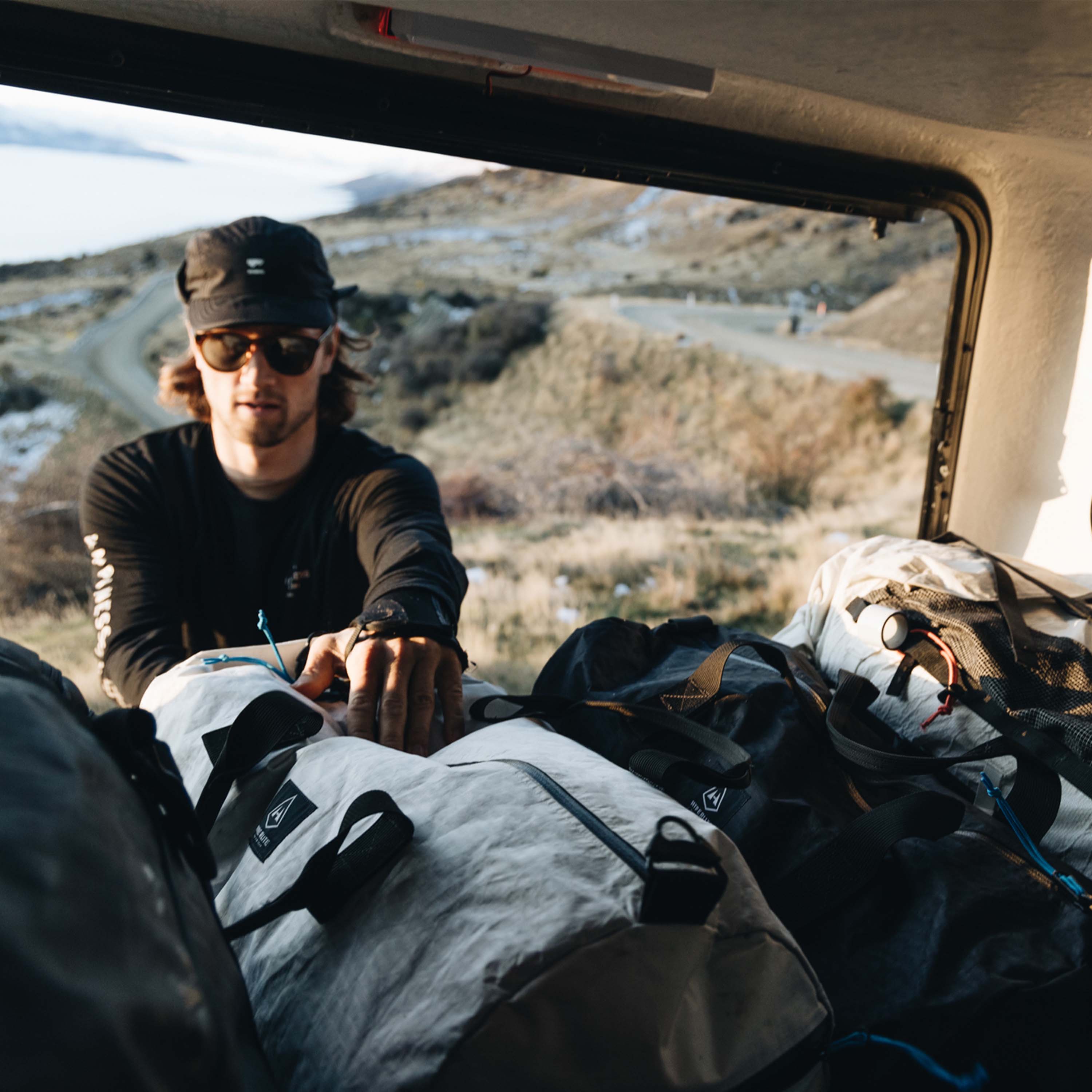 A person loading the Hyperlite Mountain Gear 30L Approach Duffel into the trunk of a car