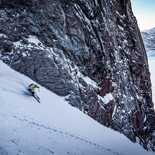 Skiier kicks up snow behind them as they ski down a snowy slope wearing the Hyperlite Mountain Gear Crux 40