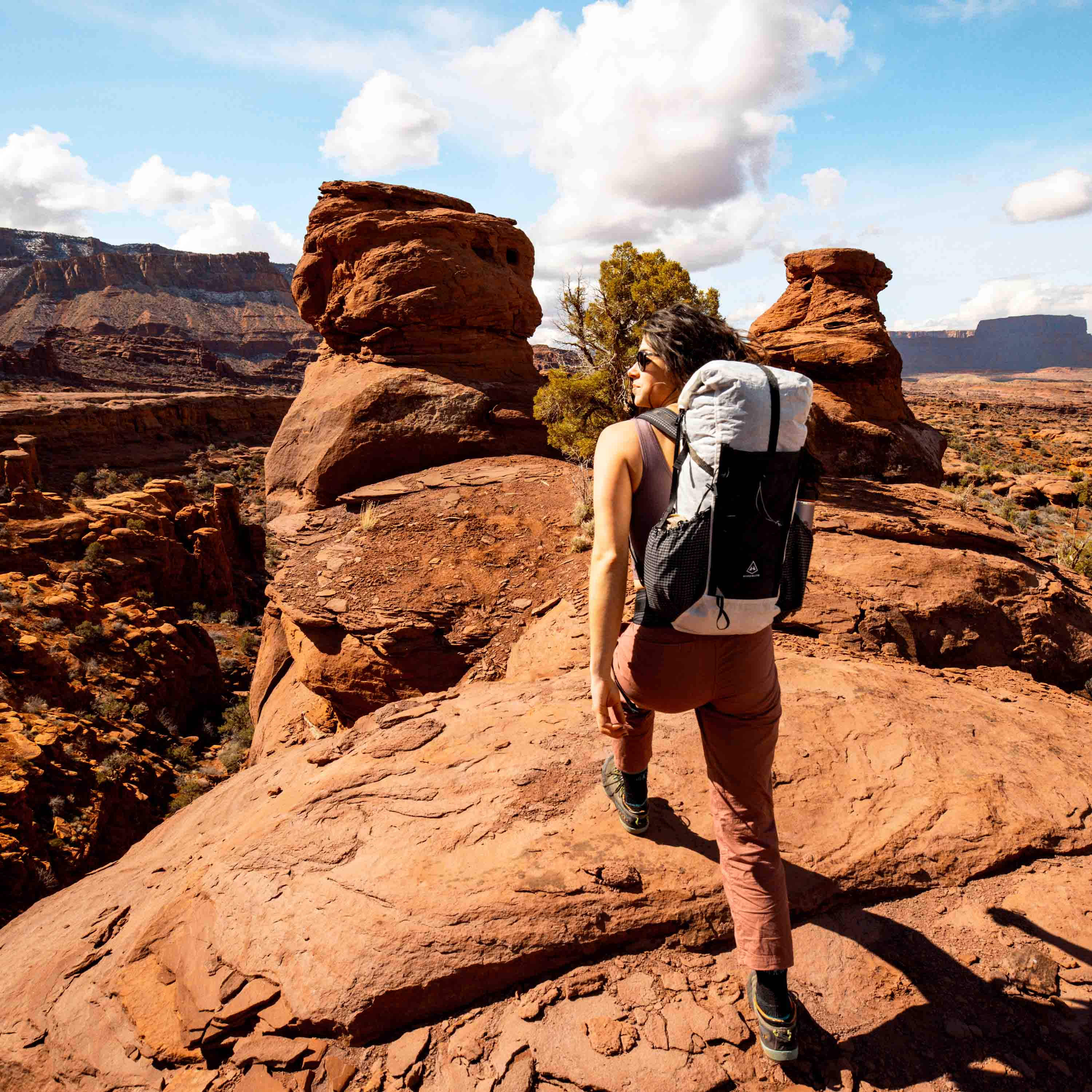 A hiker on an unmarked sandstone trail in the desert with their Hyperlite Mountain Gear Elevate 22