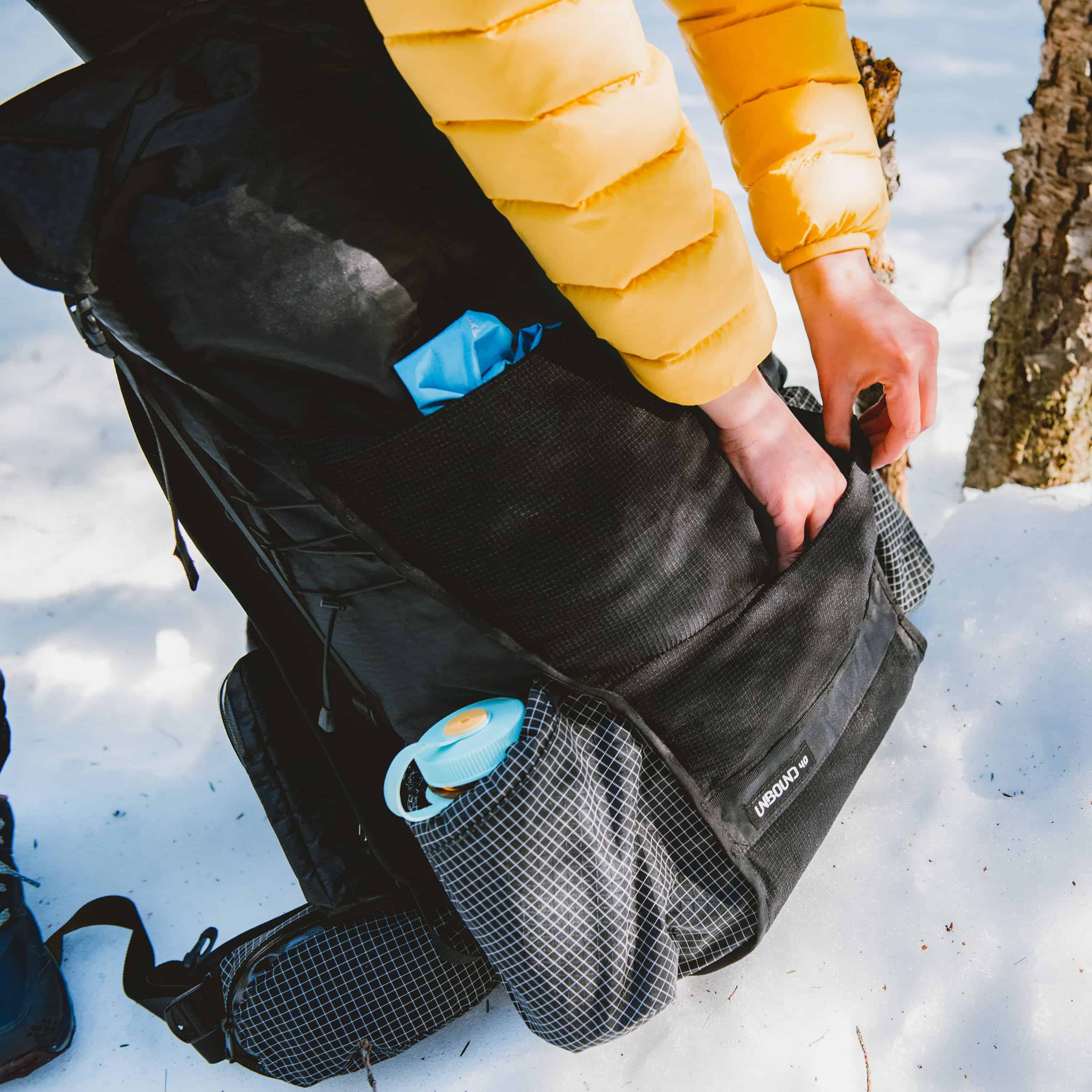 Hiker reaches into the Hyperlite Mountain Gear Unbound 40 Pack's large dual entry mesh front pocket made from durable Dyneema® Stretch Mesh