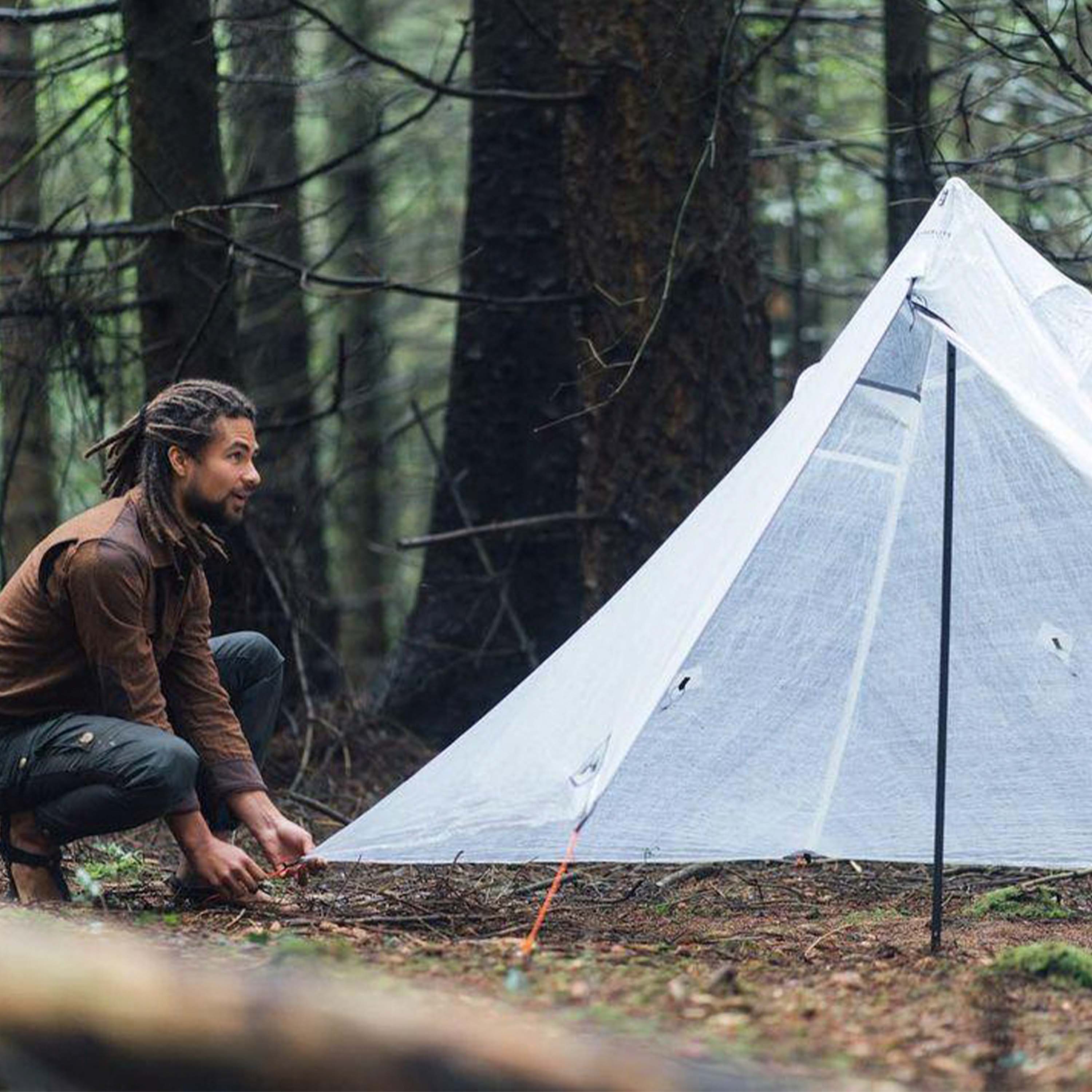 A hiker uses one of the perimeter ties out while setting up the Hyperlite Mountain Gear Mid 1 Tarp