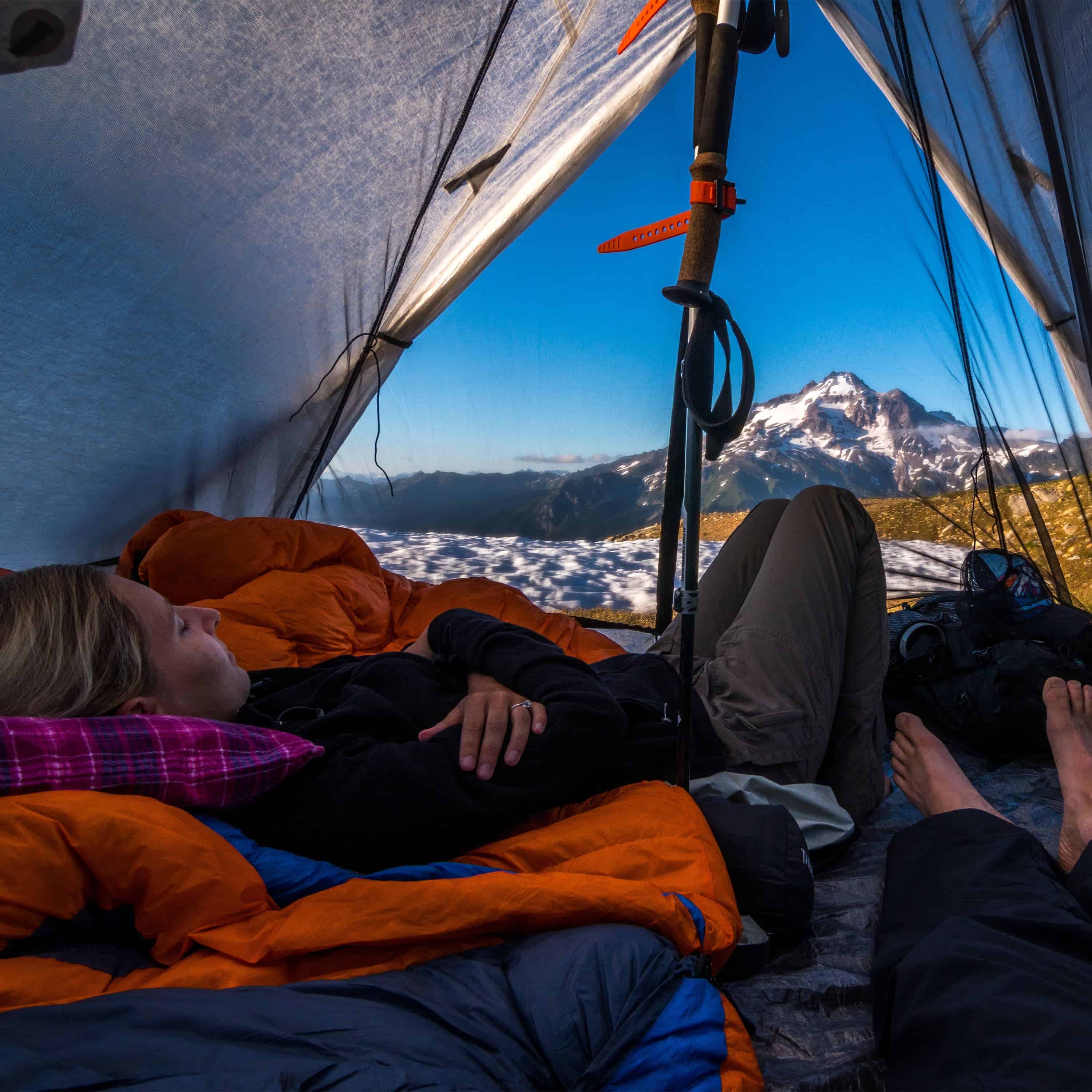 Interior view of Hyperlite Mountain Gear Shelters UltaMid 2 Insert with DCF11 Floor. A model is lying down inside tent looking out at a mountain landscape