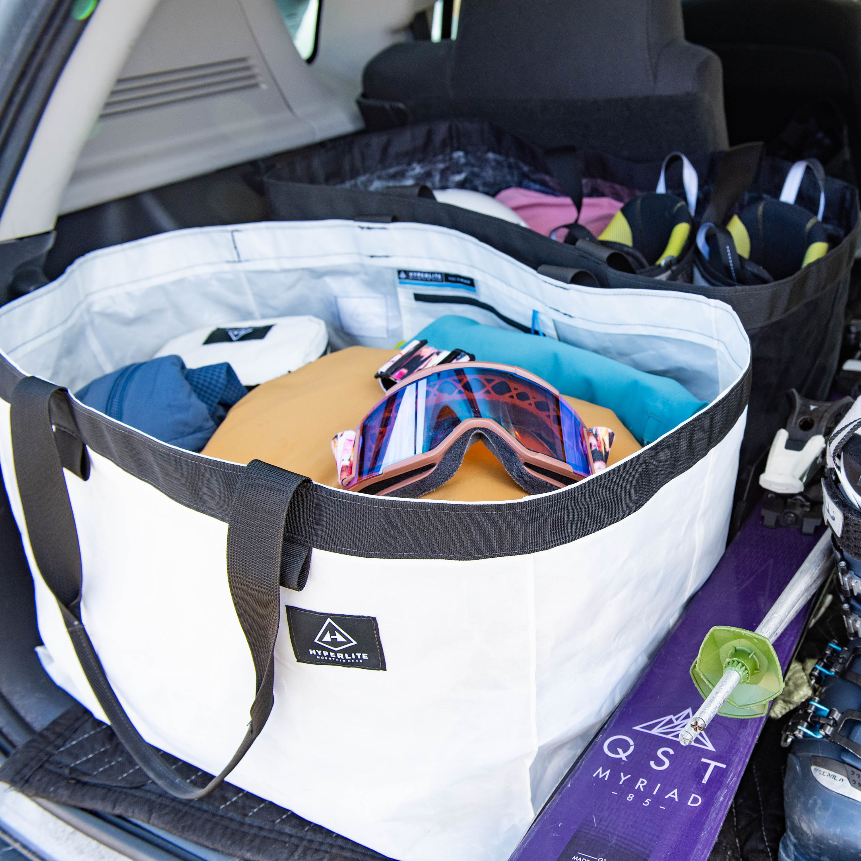 Overhead shot of Hyperlite Mountain Gear's G.O.A.T. Tote in White filled with skiing gear in the back of a vehicle 