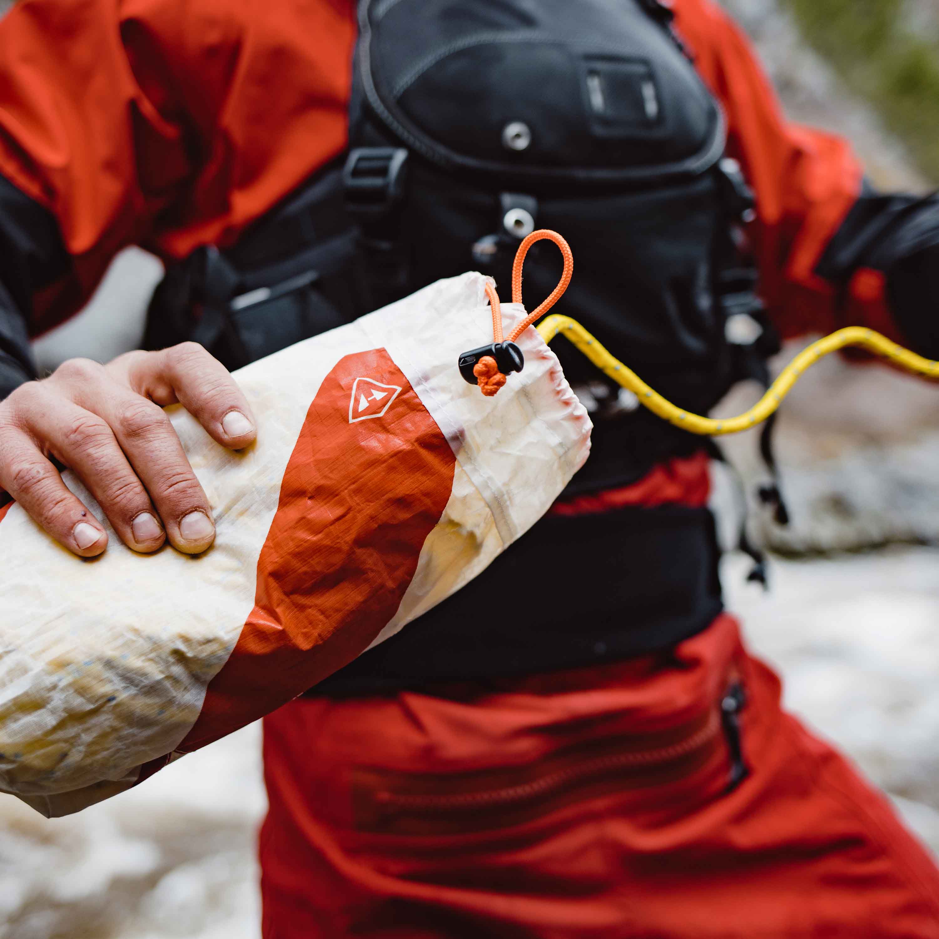 A kayaker grasps the Hyperlite Mountain Gear River Rescue Throw Bag in preparation to toss it