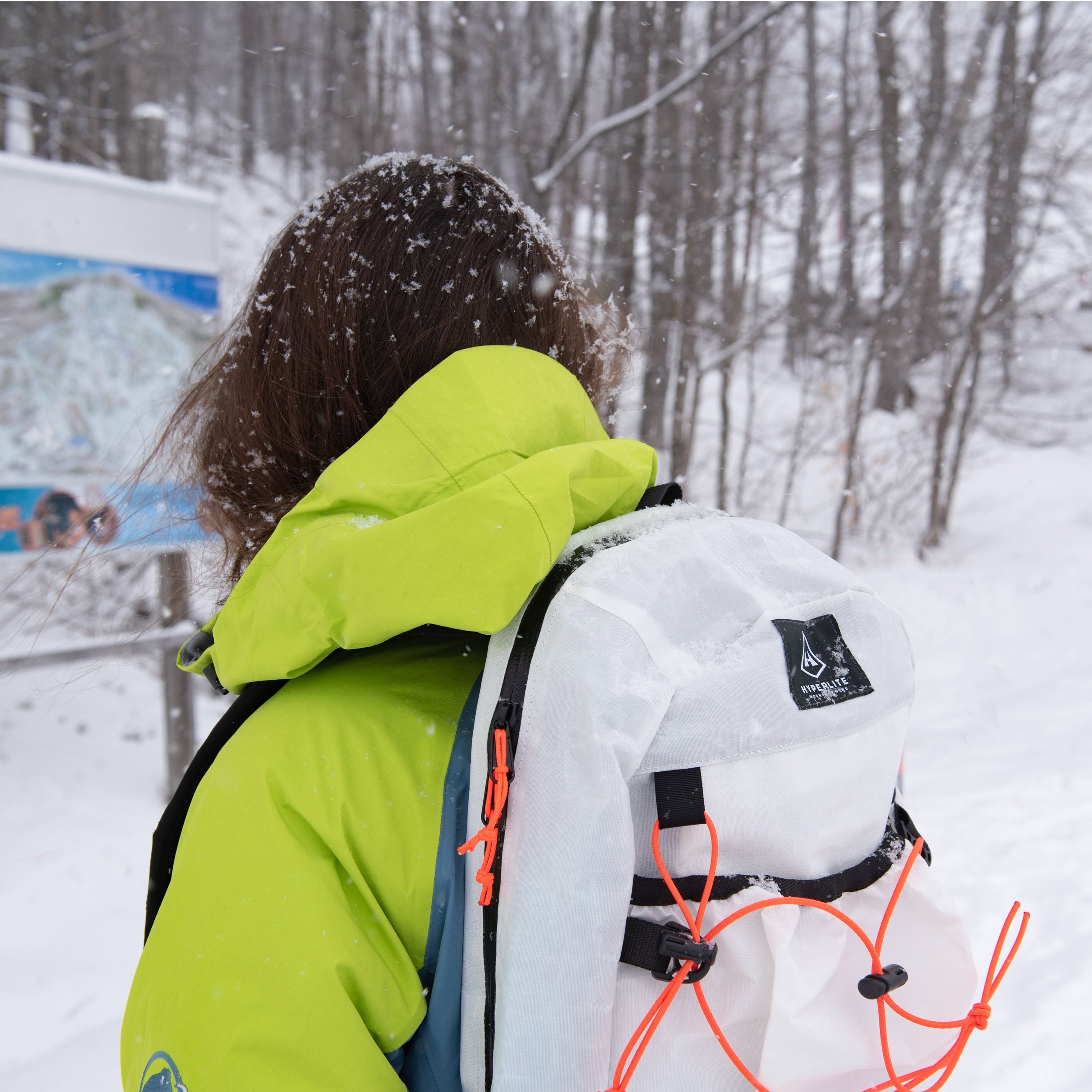 Back view of Hyperlite Mountain Gear's Daybreak 17 Pack in White on hiker in the snowy woods