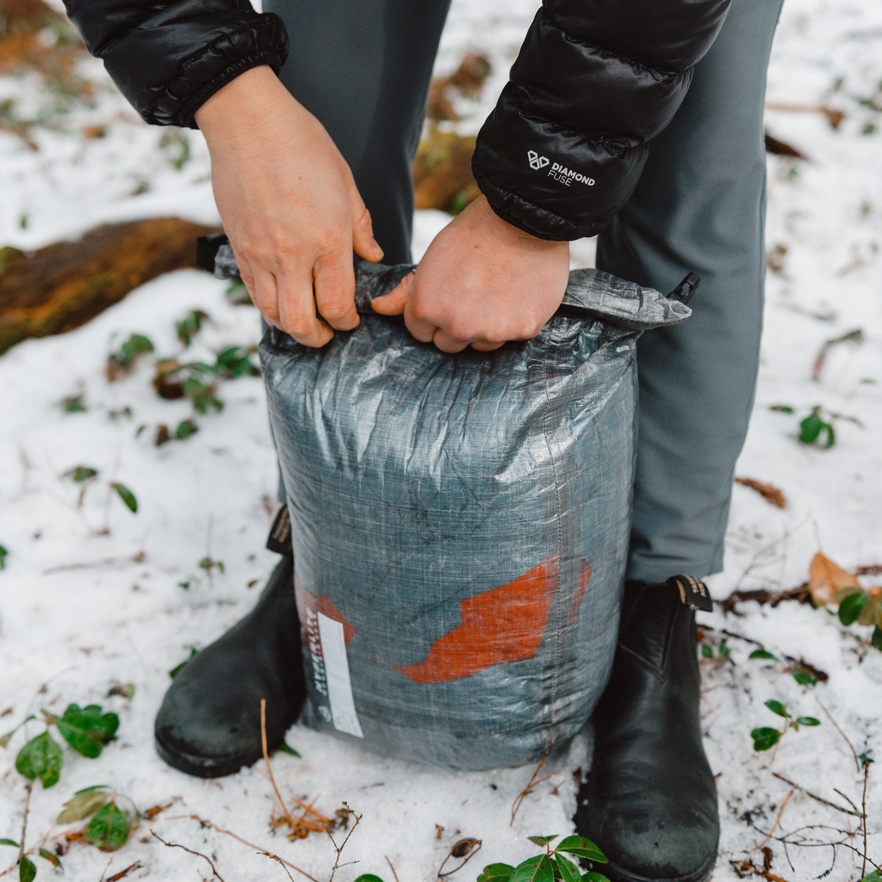 Hiker closing the rolltop on Hyperlite Mountain Gear's 12L Side Entry Pod