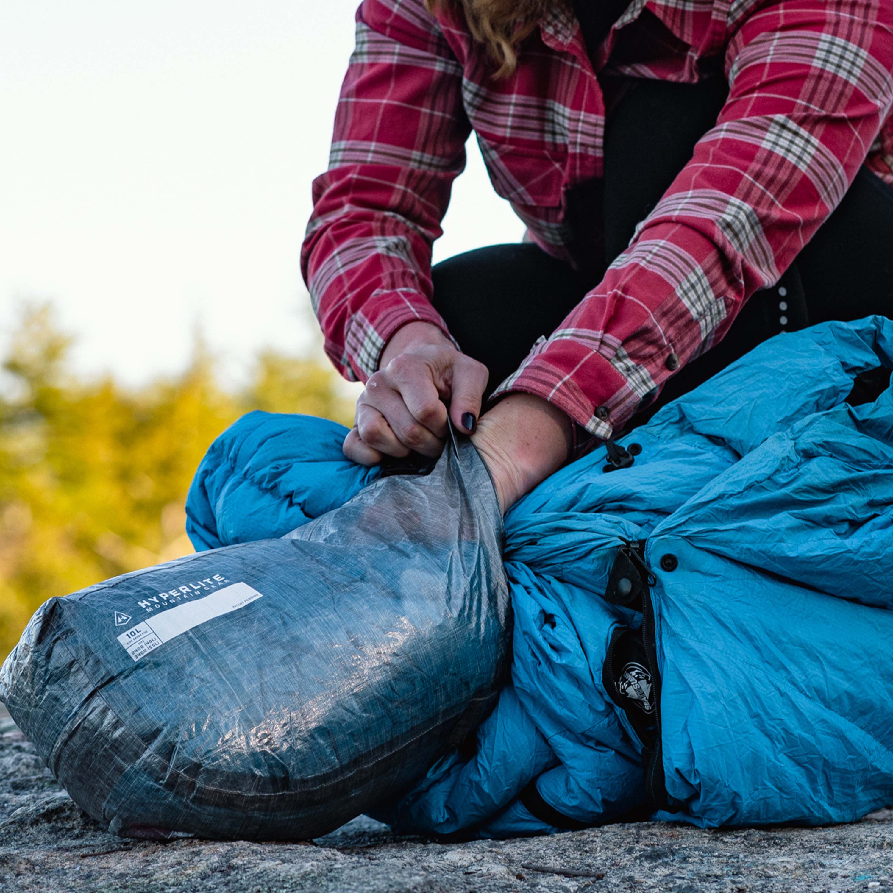 Hiker placing their sleep setp up into Hyperlite Mountain Gear's 10L Side Entry Pod