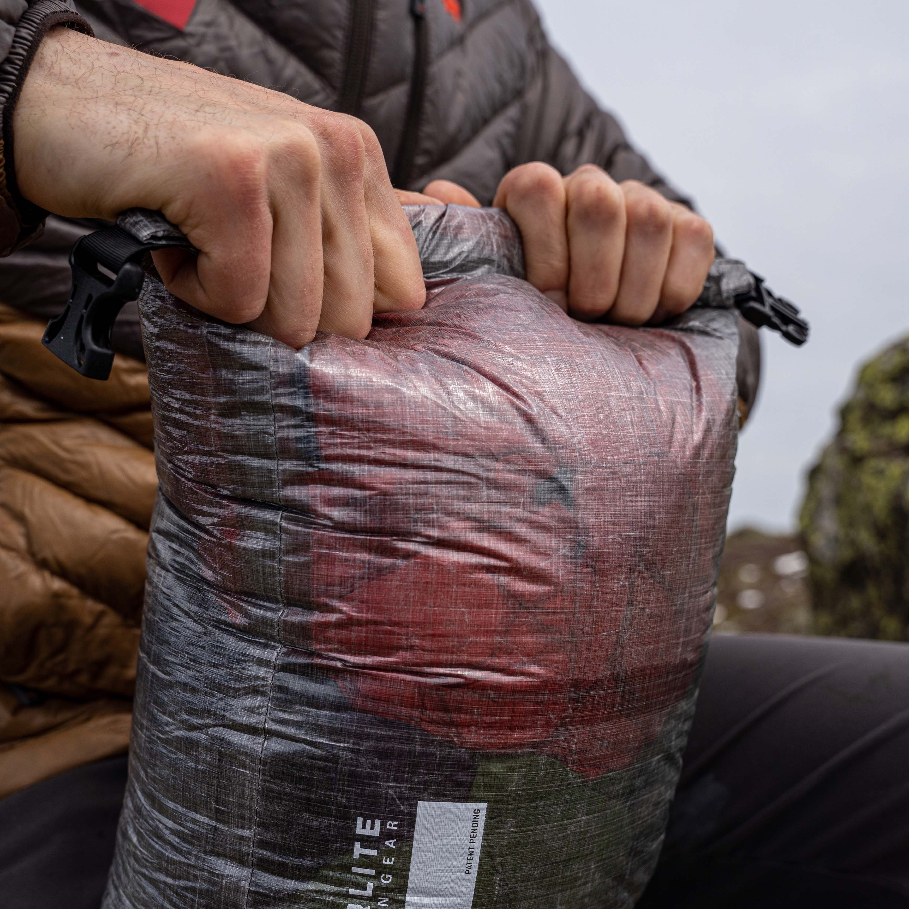 Hiker rolling the top of their Hyperlite Mountain Gear Side Entry Pod