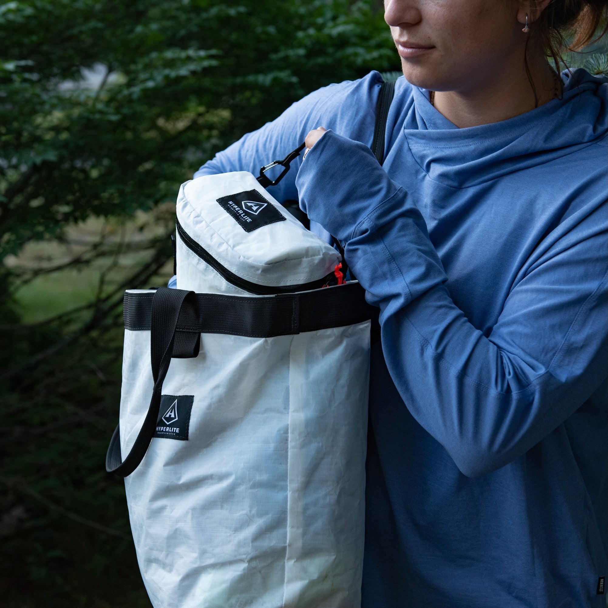 A hiker stashes the Camera Pod in their GOAT Tote, both sold as a part of the Hyperlite Mountain Gear Perfect Shot Bundle