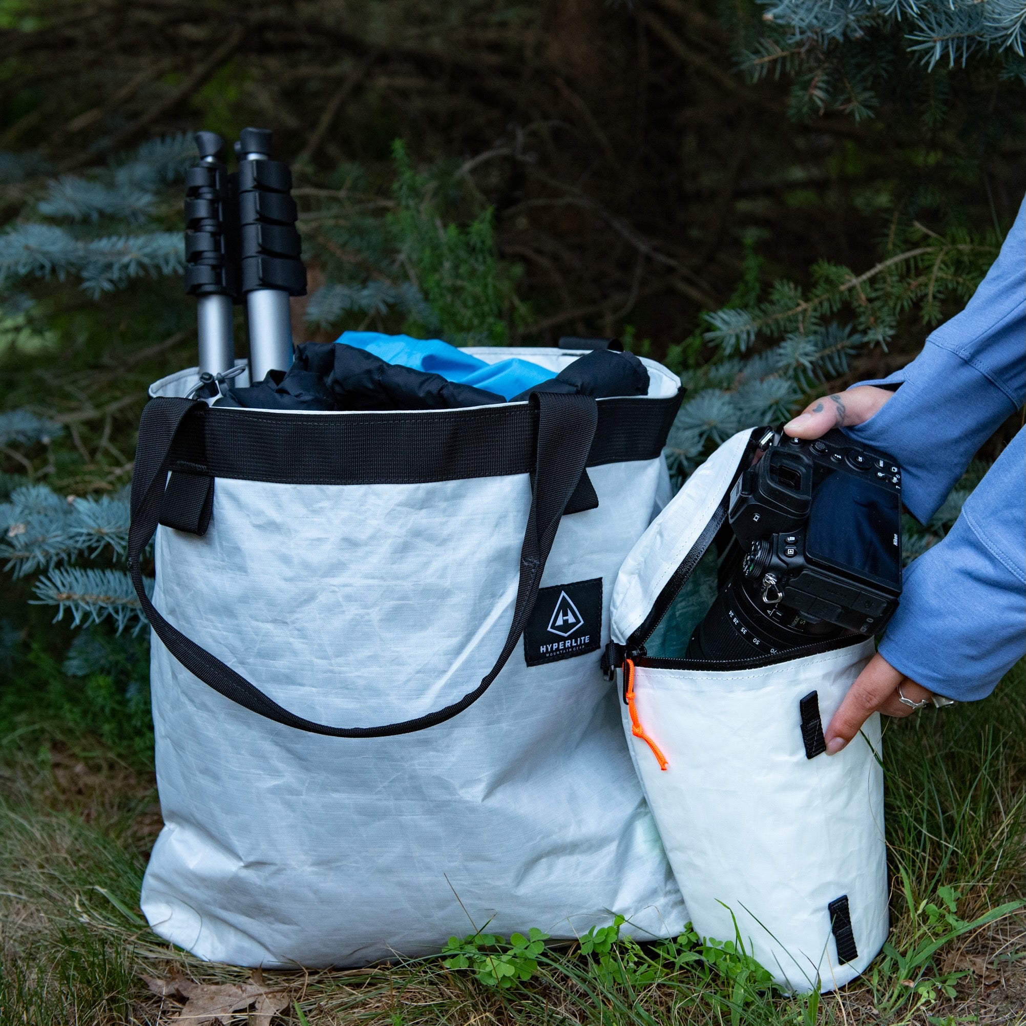 View of the Hyperlite Mountain Gear Perfect Shot Bundle as a hiker stashes their camera away in the Large Camera Pod in White