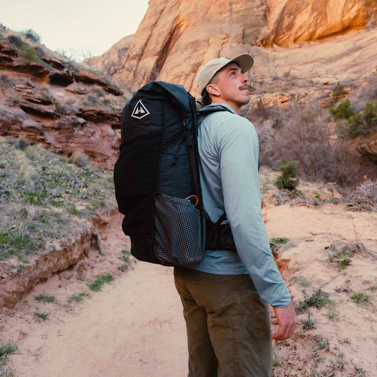 Hiker gazes up the canyon on the trail wearing the Hyperlite Mountain Gear Unbound 55 in Black