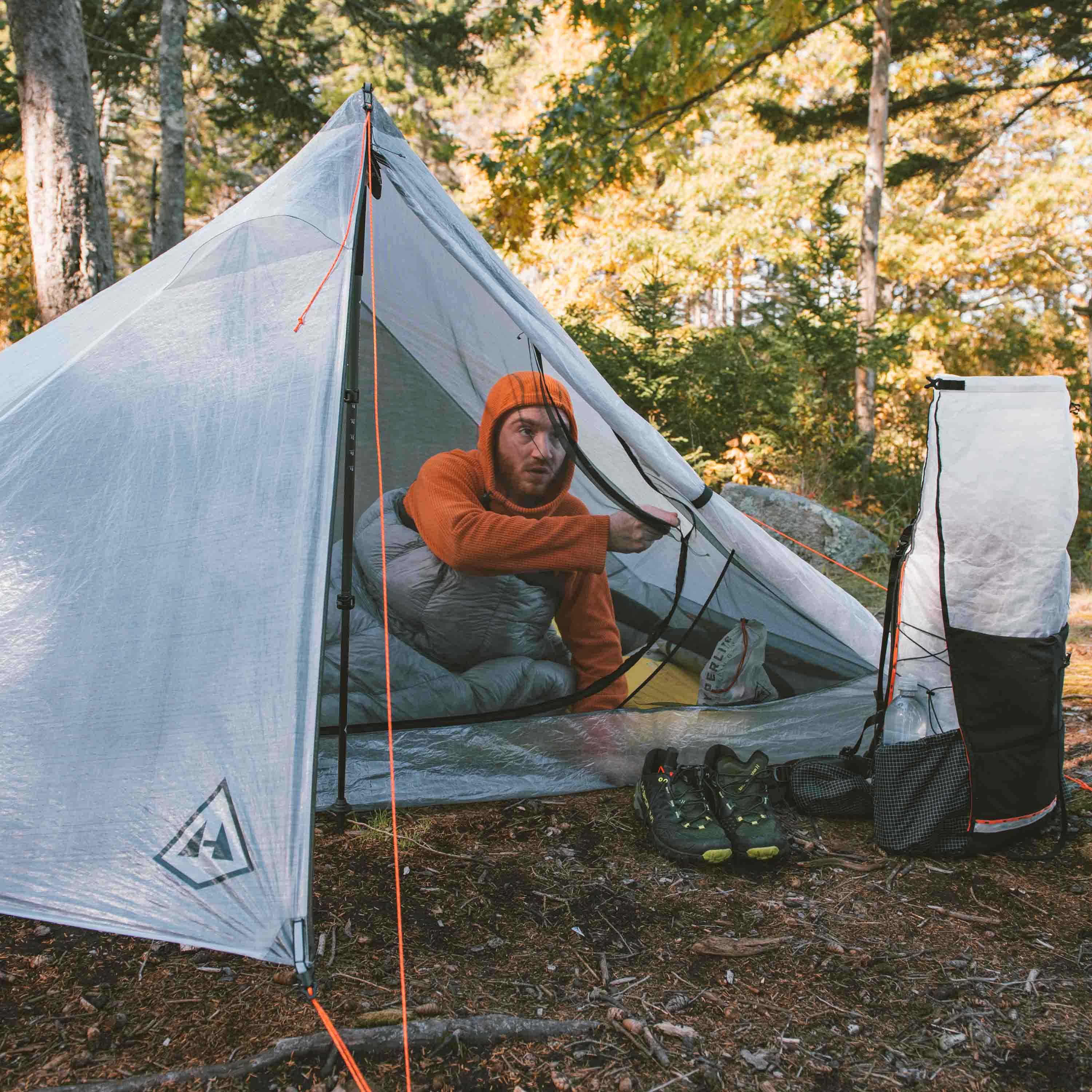 Lifestyle shot of a camper laying in the Hyperlite Mountain Gear Unbound 2P Tent with one of the vestibule doors tied back