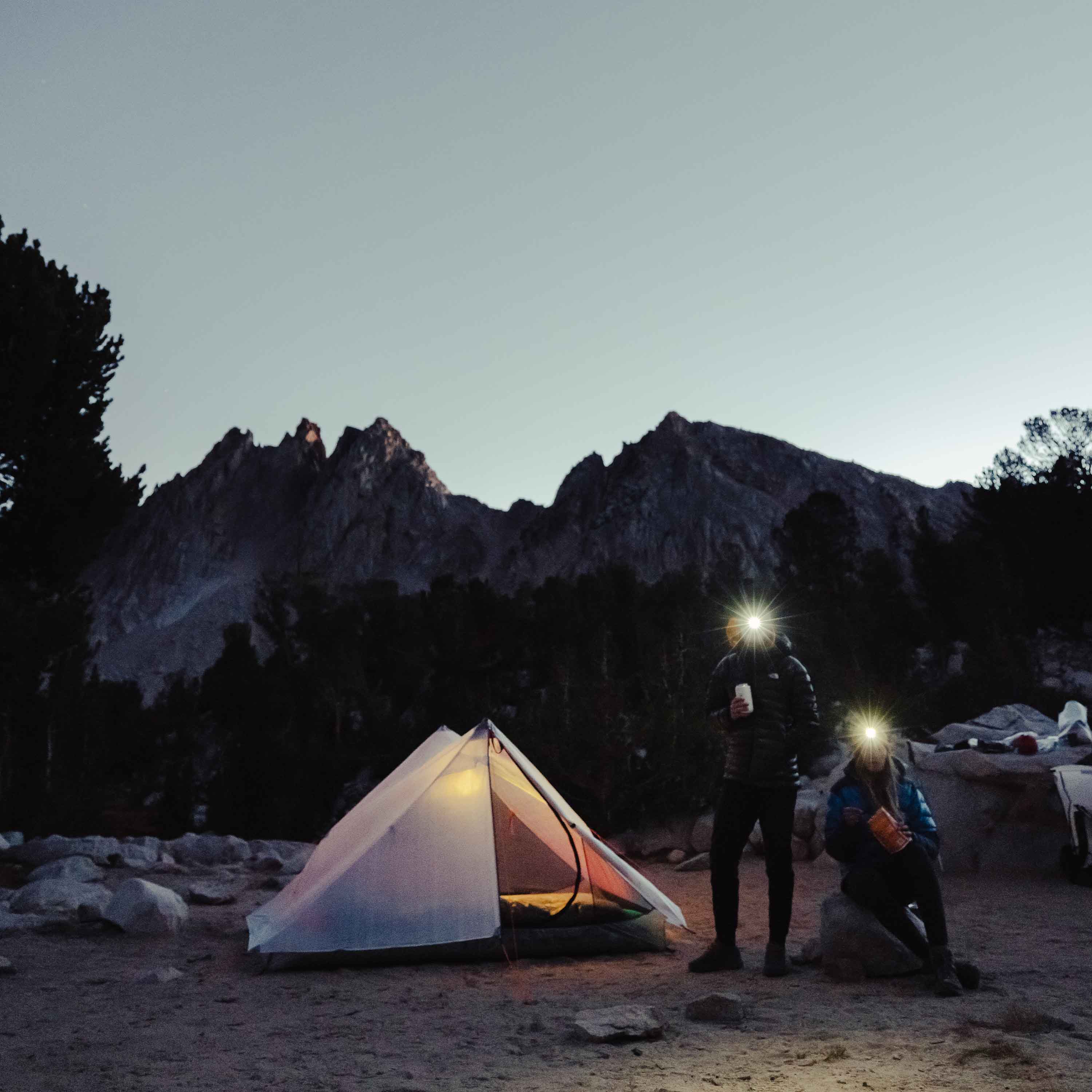 Hyperlite Mountain Gear Unbound 2P Tent with two headlight wearing campers looking on as night approaches