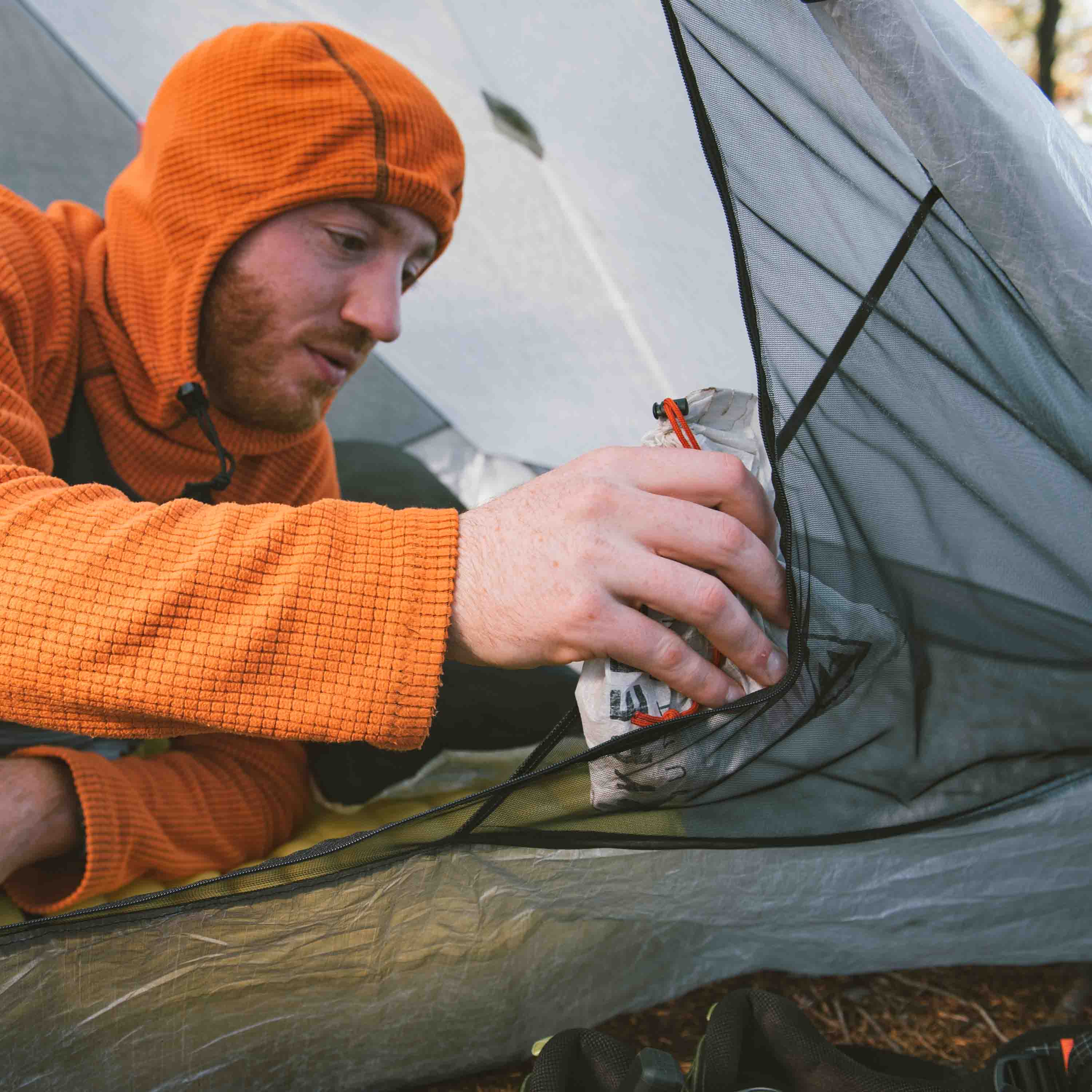 Hyperlite Mountain Gear Unbound 2P Tent features mesh side pockets to stash gear as this camper is seen doing